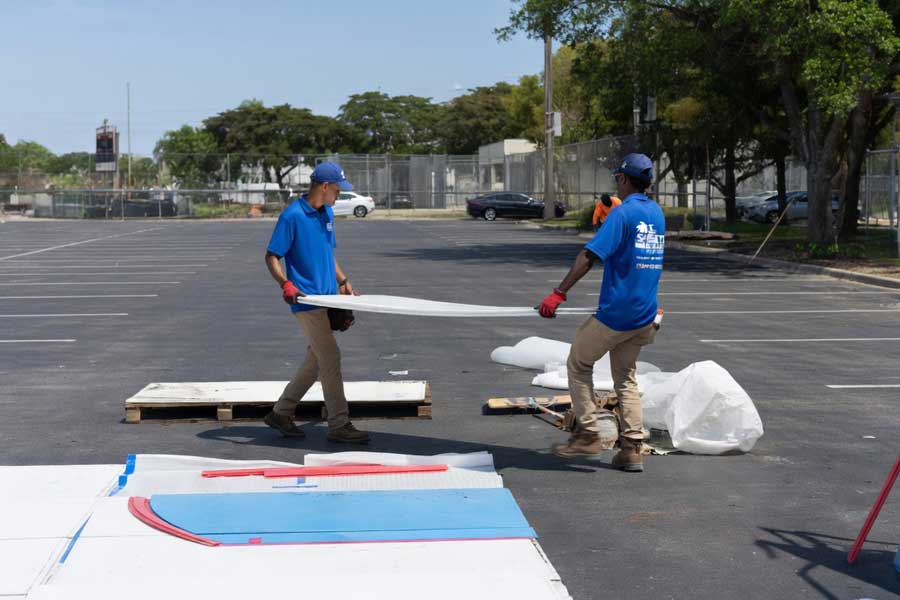 Uniformed Ice Sheets crew members assembling the mobile rink dasher boards